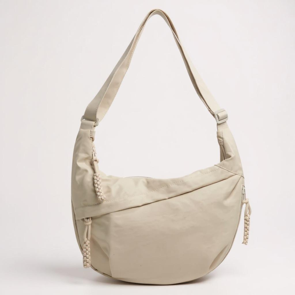 Beige crescent shoulder bag with zip pockets, front product view.