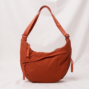 Orange crescent shoulder bag with zip pockets, front product view.