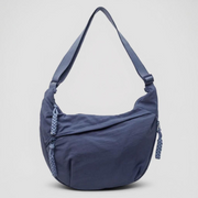 Blue crescent shoulder bag with zip pockets, front product view.