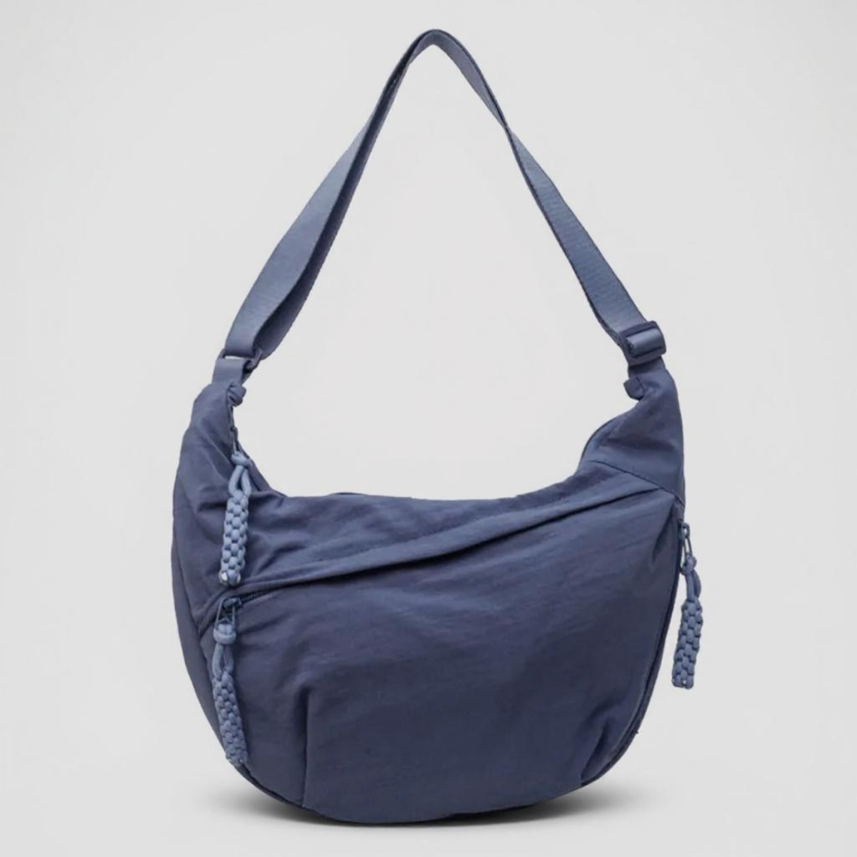 Blue crescent shoulder bag with zip pockets, front product view.
