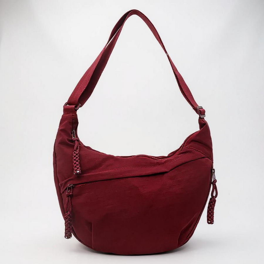Burgundy crescent shoulder bag with zip pockets, front product view.