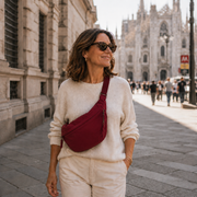 Burgundy crescent shoulder bag with zip pockets, bag worn across the body.