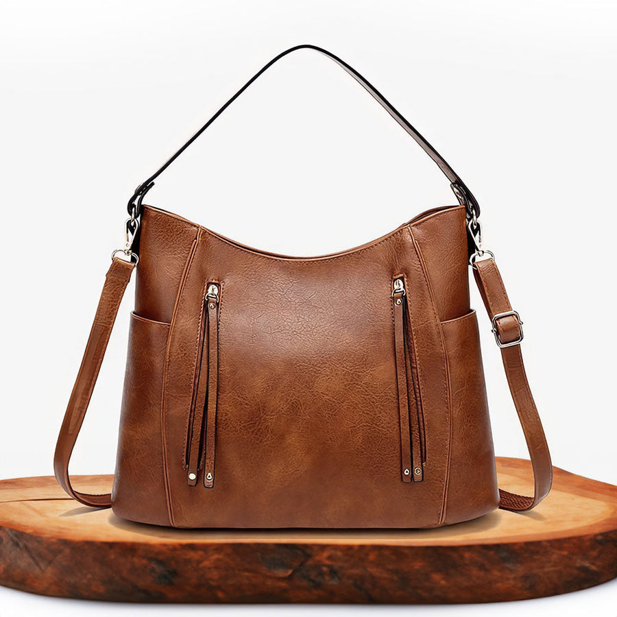 Women's handbag with a shoulder strap, a front zip and a curved outline