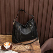 Women's handbag with a shoulder strap, a front zip and a curved outline