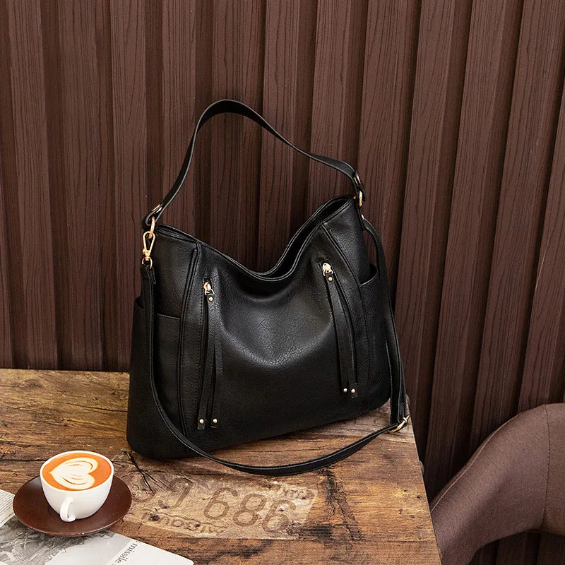 Women's handbag with a shoulder strap, a front zip and a curved outline