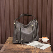 Women's handbag with a shoulder strap, a front zip and a curved outline